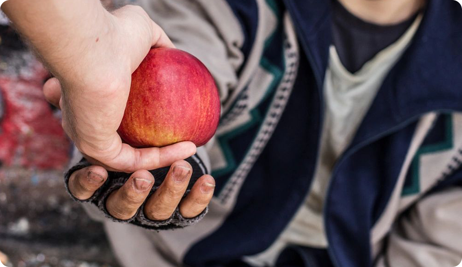 A man is handing an apple to another person.