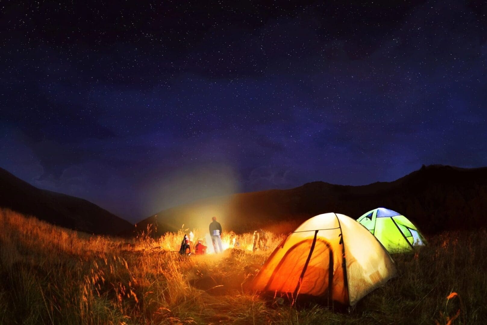 A group of people camping in the dark.